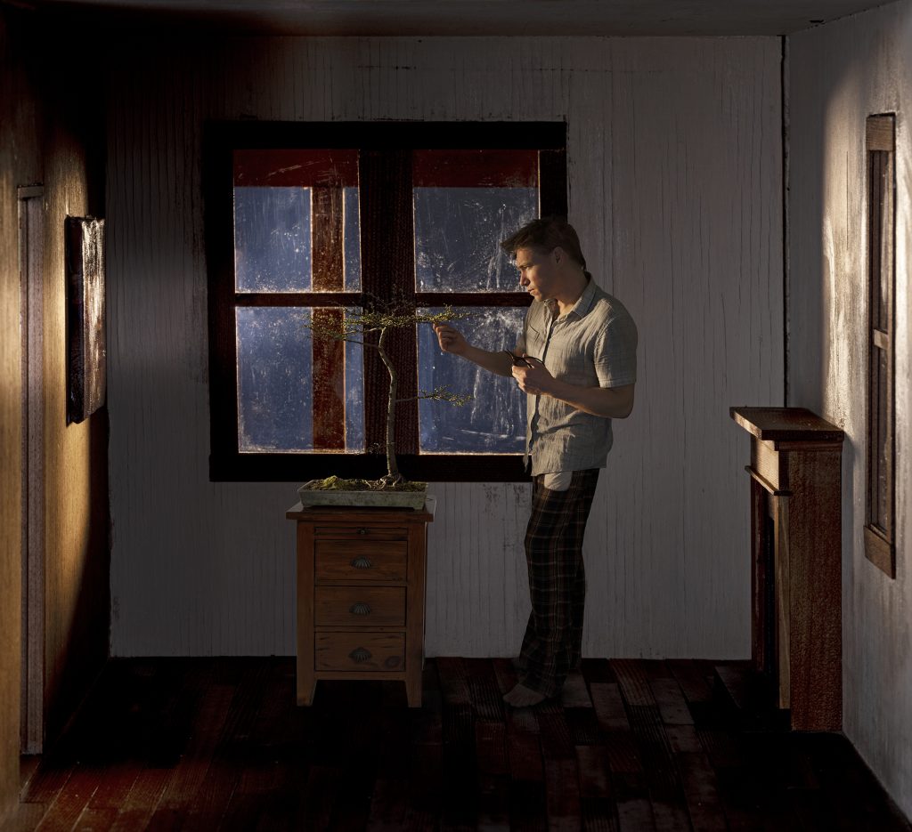 figure standing in front of a window, attending to a bonsai on a table, bright light coming through the window onto detailed surfaces of the room and surrounding walls